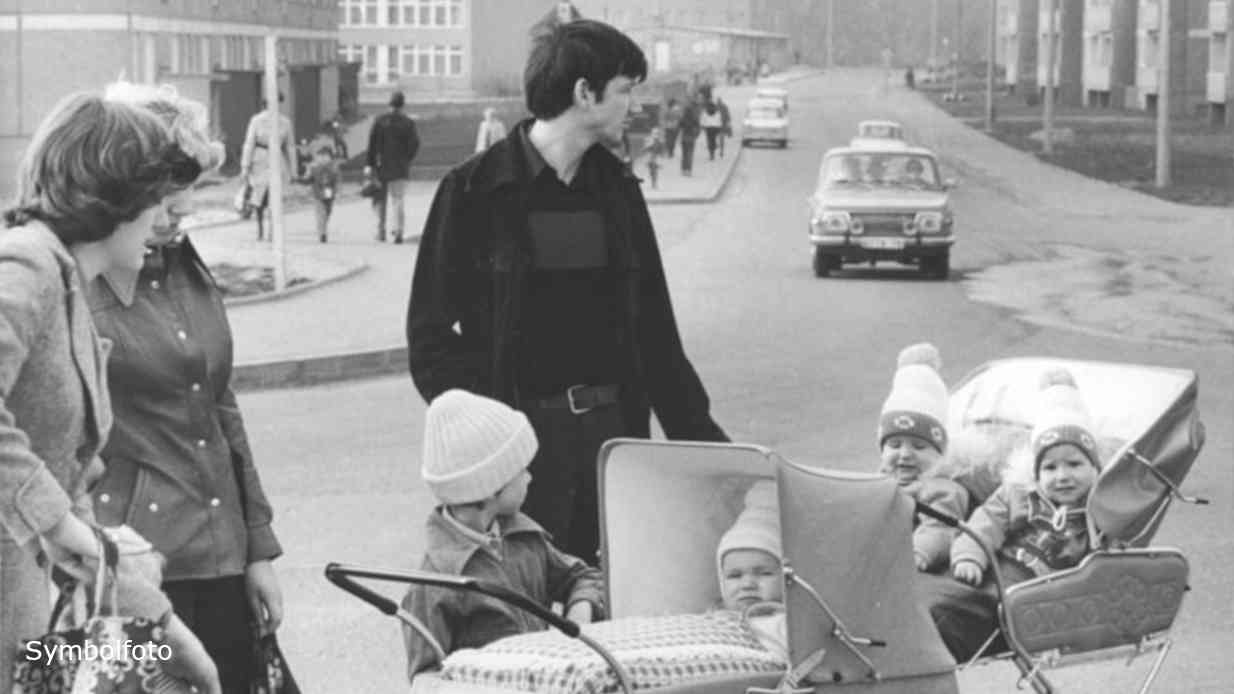 Eltern mit Kindern im Kinderwagen auf einer Straße.